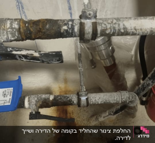 צנרת מים מעוקלת וחלודה עם סימני נזילה וחלודה על הקיר